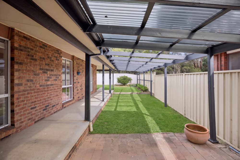 Covered rear entertaining area with paving and lawn